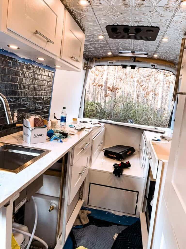Unfinished campervan build with some finished cabinets, kitchen backsplash tile and countertop