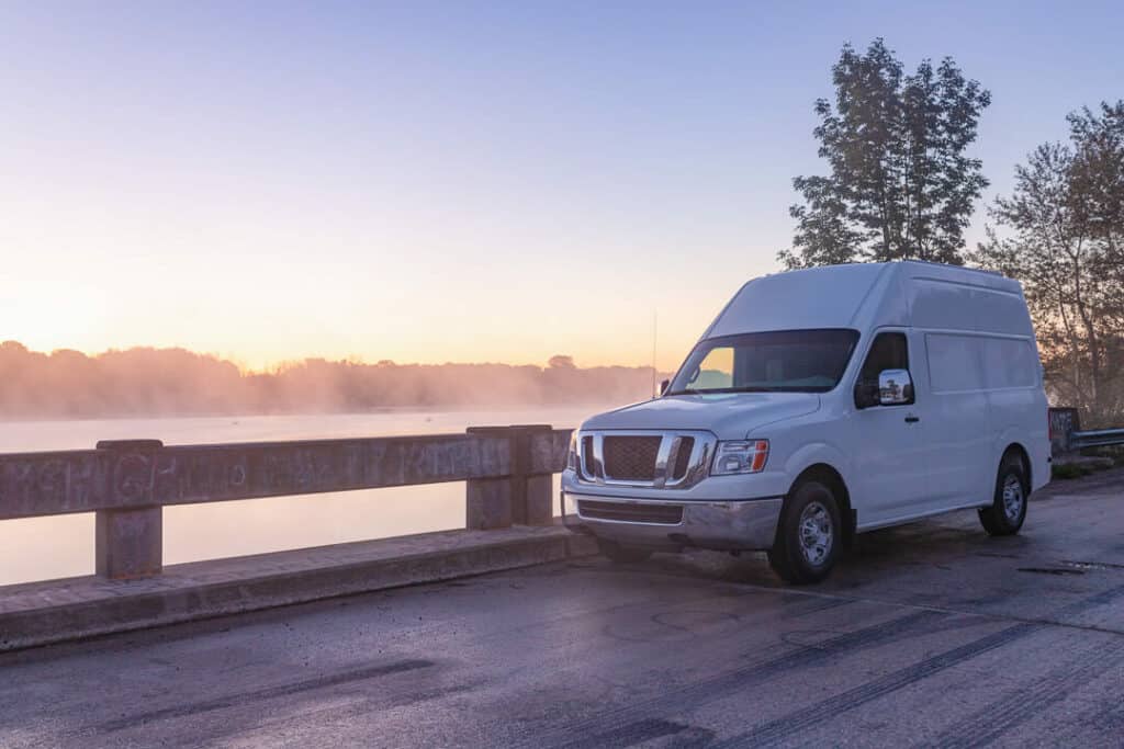 Nissan NV van parked on a bridge with fog in the background