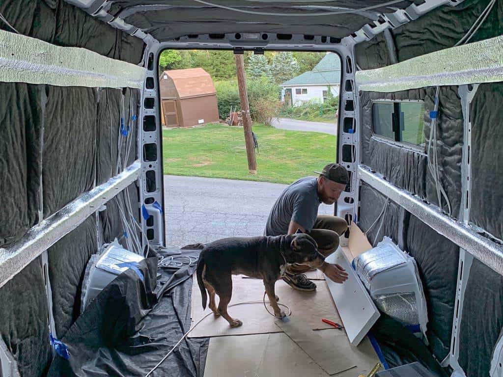 Man installing insulation in a unfinished van build