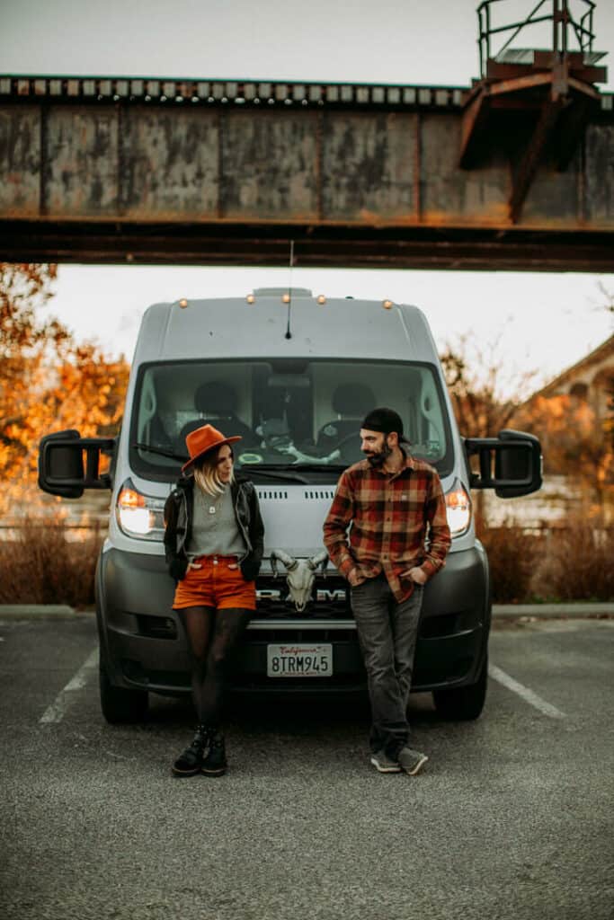 Couple standing in front of dodge ram campervan