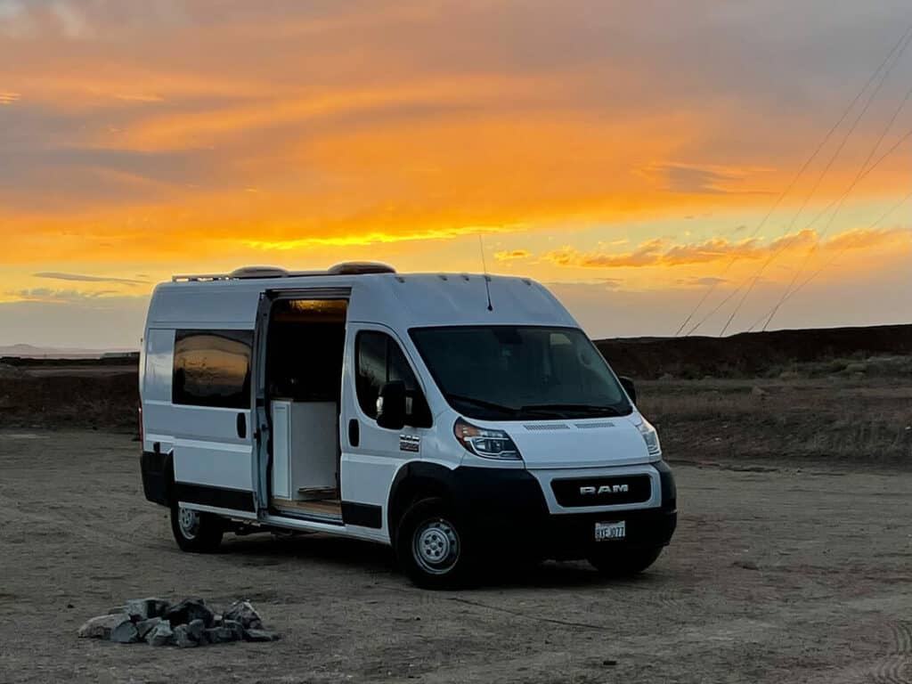 Dodge promaster Camper van parked in a dirt lot at sunset