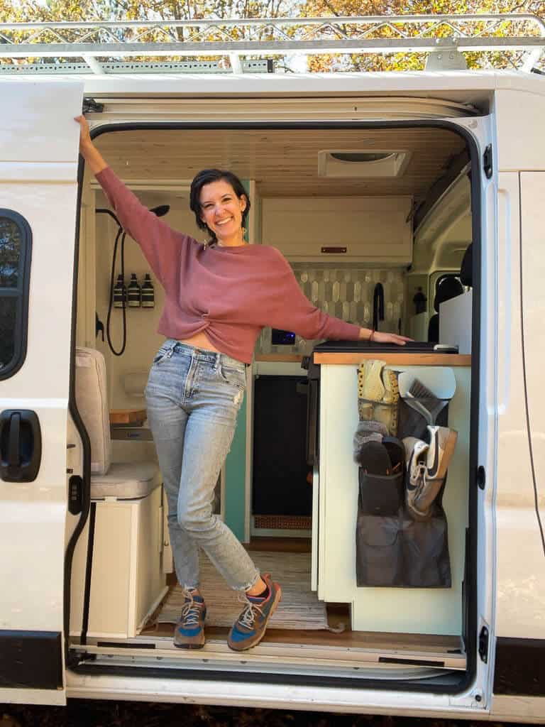 Woman posing in the doorway of her self built camper van