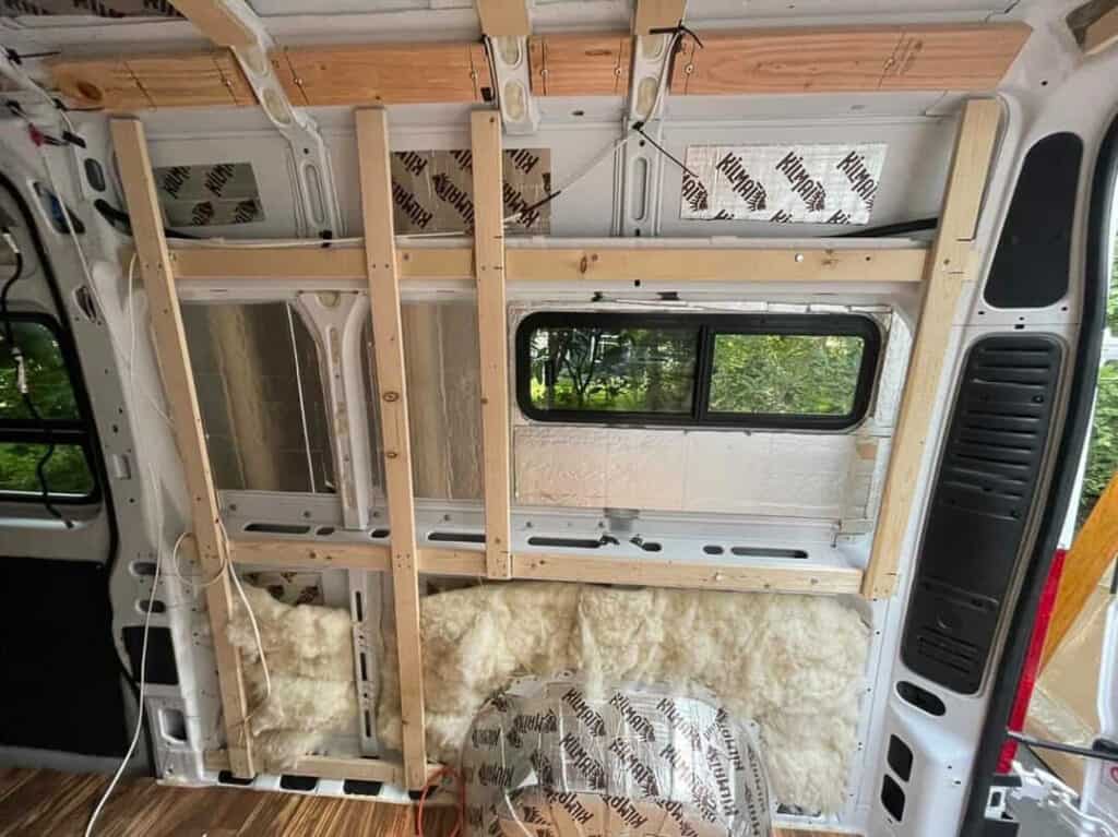 a framed out wall with a window and insulation in a unfinished campervan build
