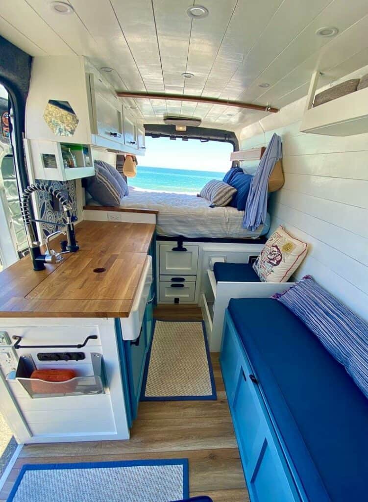A camper van with a bench seat, full kitchen, toilet and platform bed