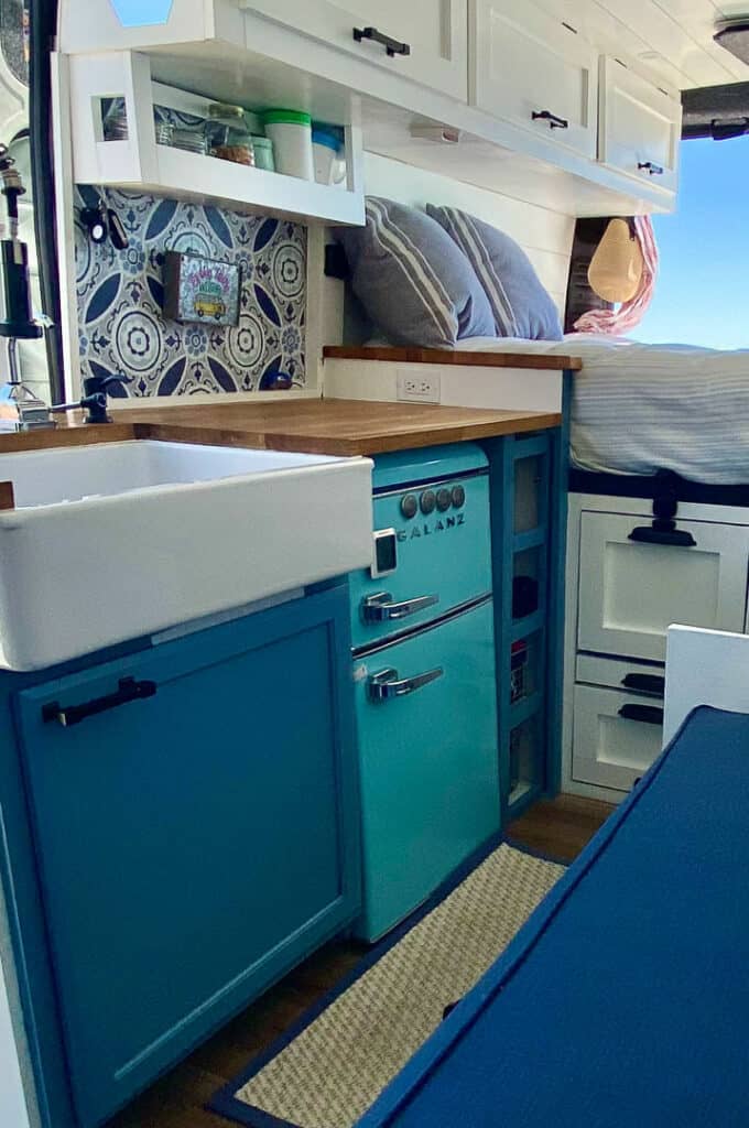 Camper van kitchen with butcher block counters, farmhouse sink and retro fridge