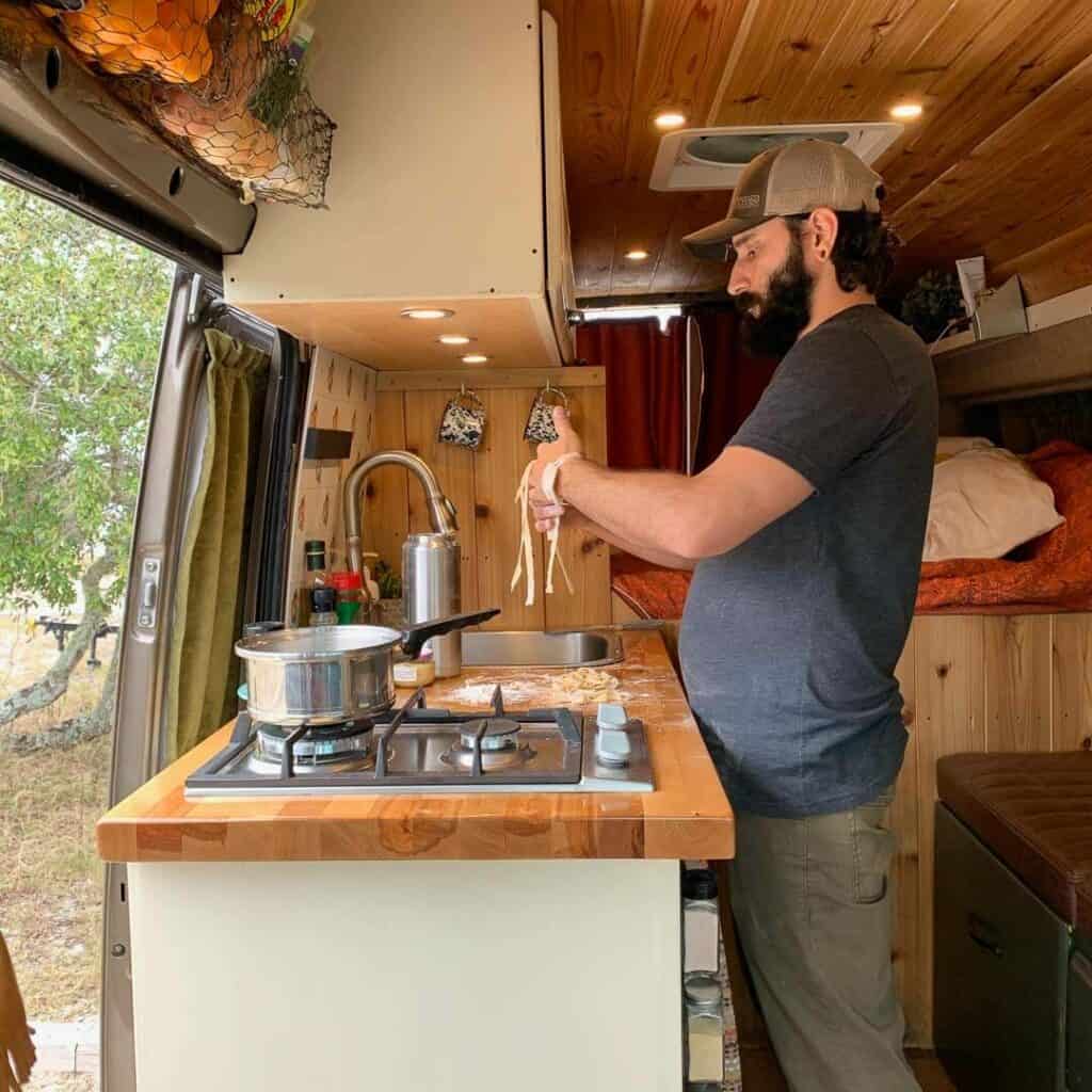 A man cooking inside of a campervan