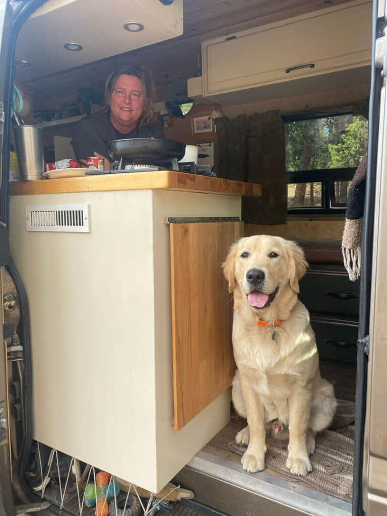 woman and dog posing inside a camper van 