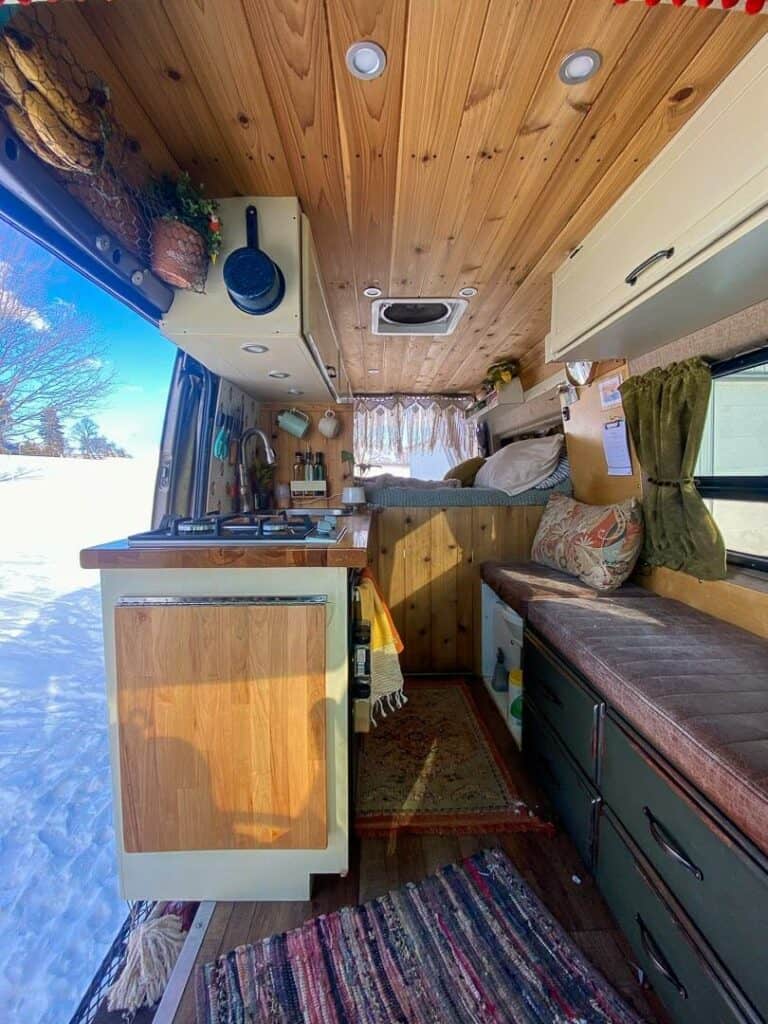 Interior of a sprinter camper van build with a full kitchen, couch and a bed