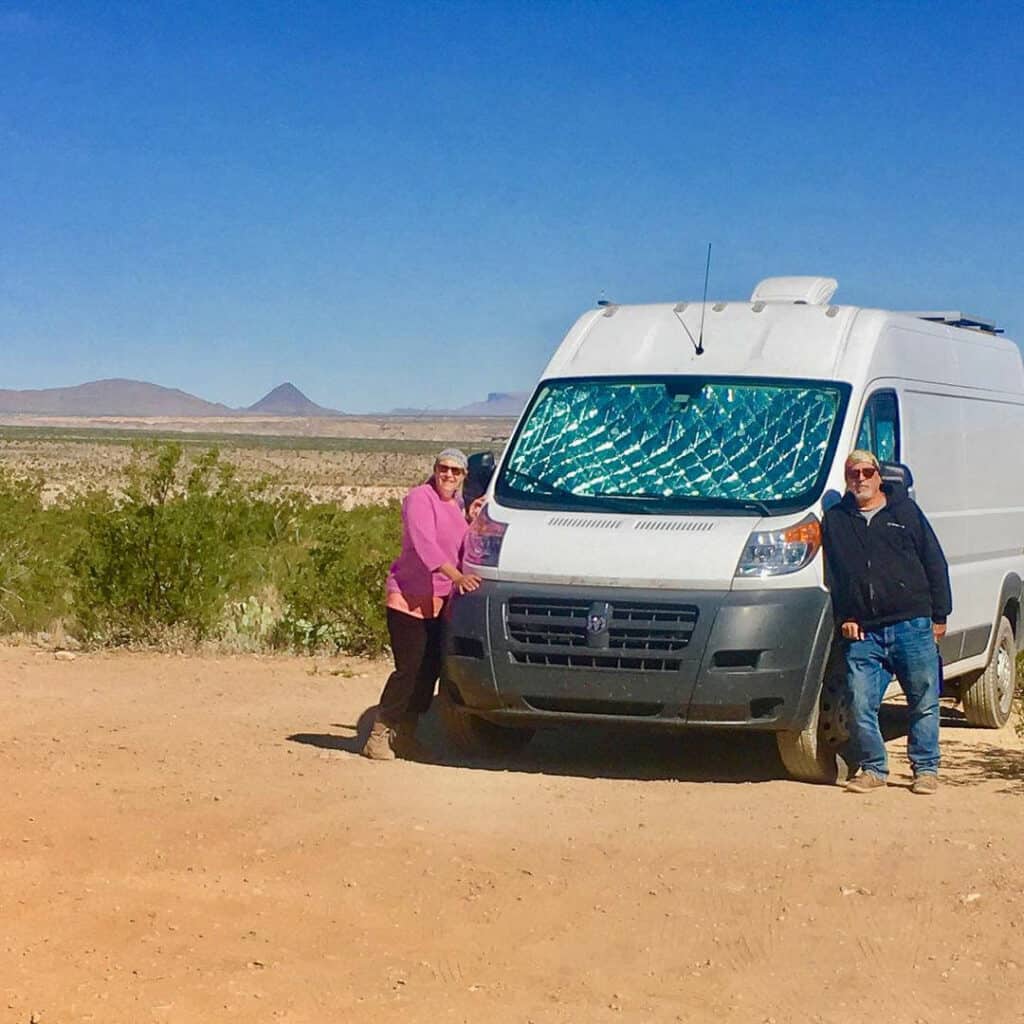 couple standing by campervan in desert