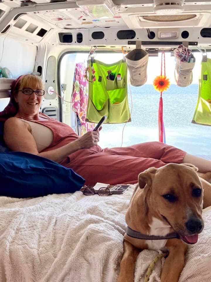 woman on campervan bed with view of ocean