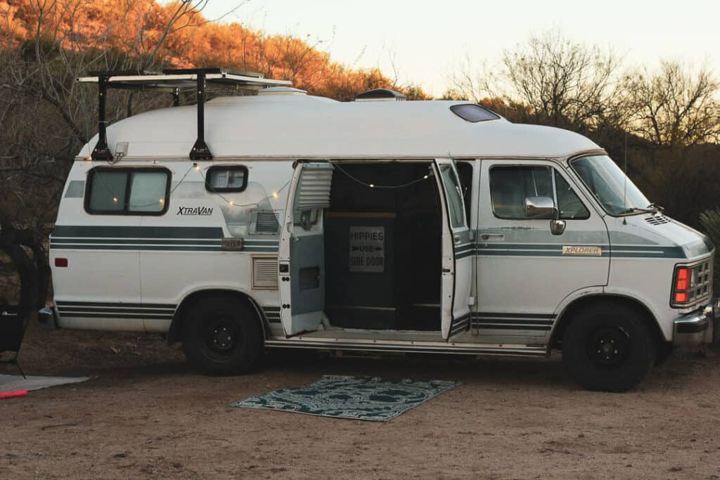 Old Dodge Xplorer camper van parked at a campsite with its doors open