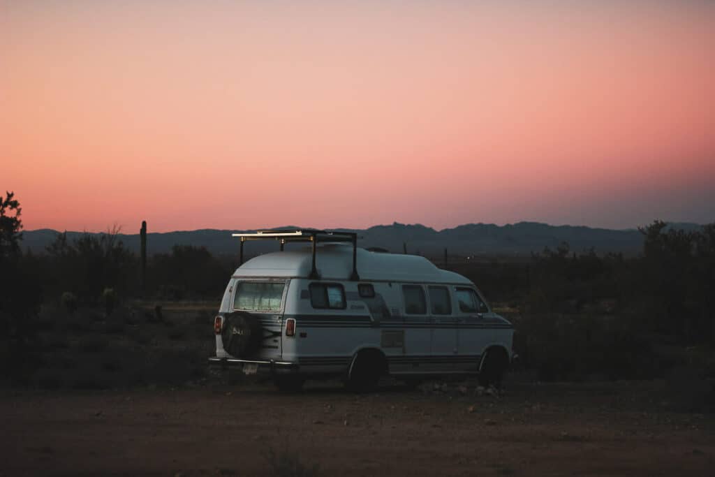A camper van parked at a campsite at sunset