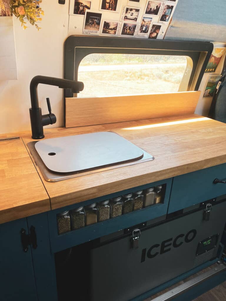 Butcher block counters and a small sink and faucet in a camper van kitchen