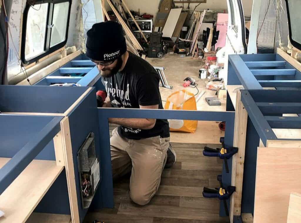 A man building cabinet frames in a van