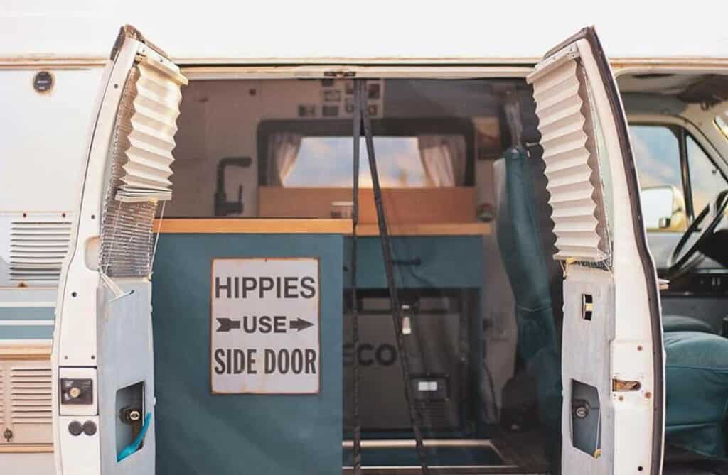 A camper van with its side doors open showing a sign that says 